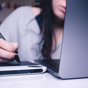 woman using drawing pad while sitting in front of laptop